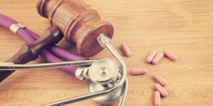 gavel, stethoscope and pills on wooden background